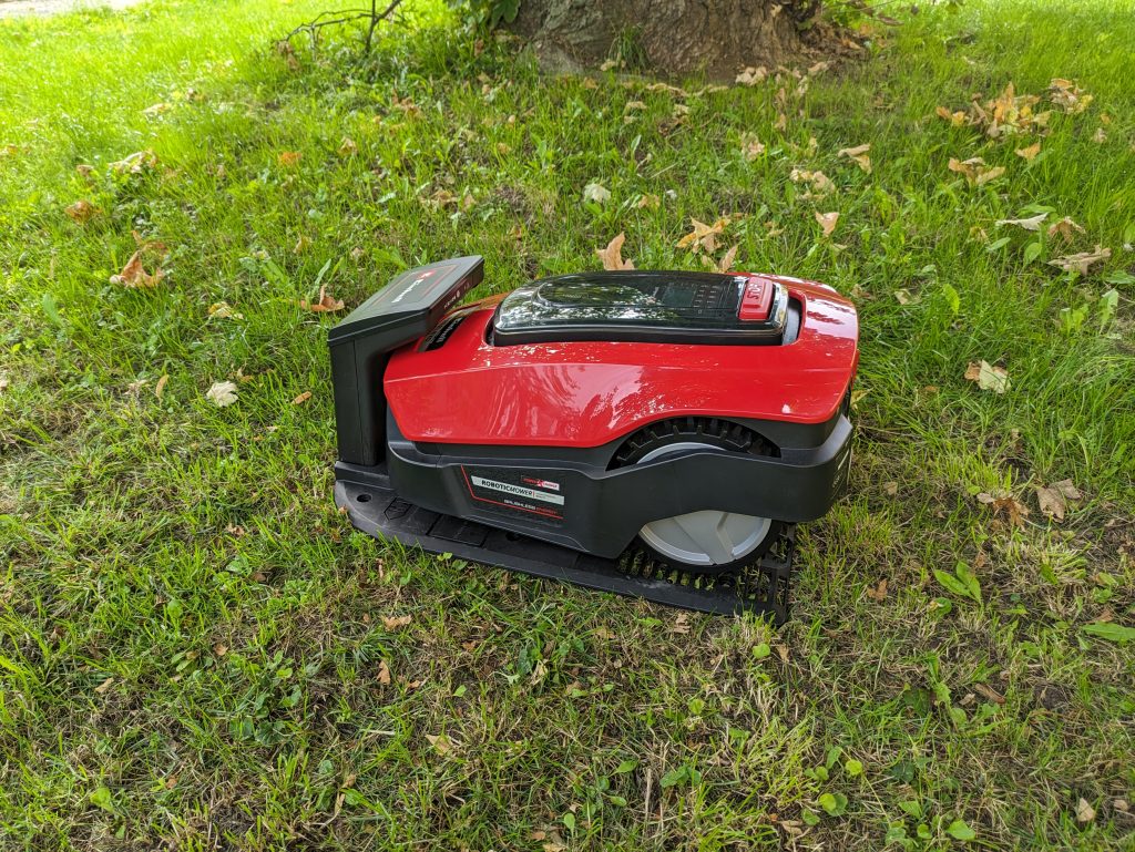 Einhell FREELEXO 1200 LCD BT Mähroboter auf der Wiese und in der Ladestation