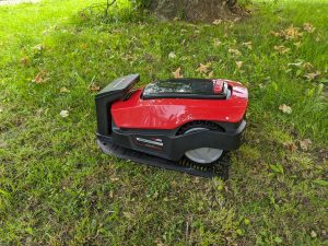 Einhell FREELEXO 1200 LCD BT Mähroboter auf der Wiese und in der Ladestation