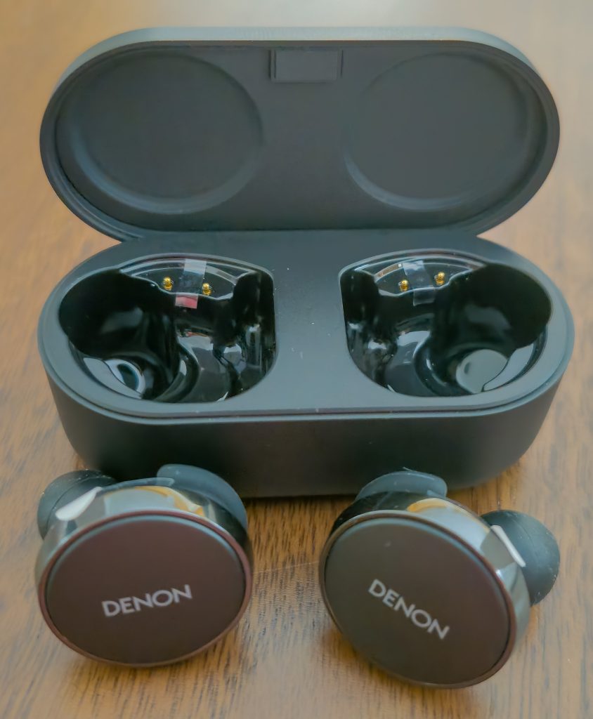 Denon PerL Pro Kopfhörer vor geöffnetem Ladecase