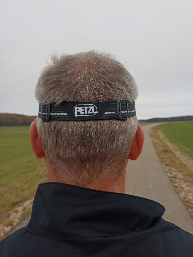 PETZ Actik Core Stirnlampe, auf Kopf bei Mann, von hinten