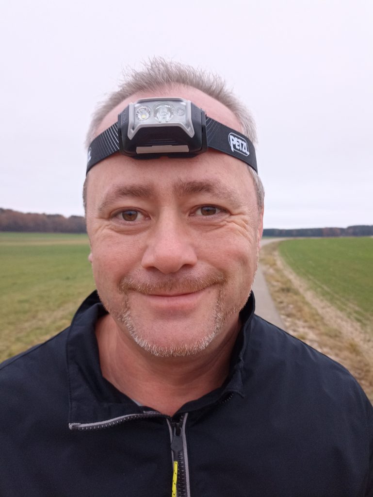 PETZL Actik Core Stirnlampe, auf Kopf bei Mann, von vorne