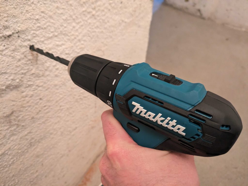Makita DF333DSAE Akkuschrauber beim Bohren in Mauerwerk