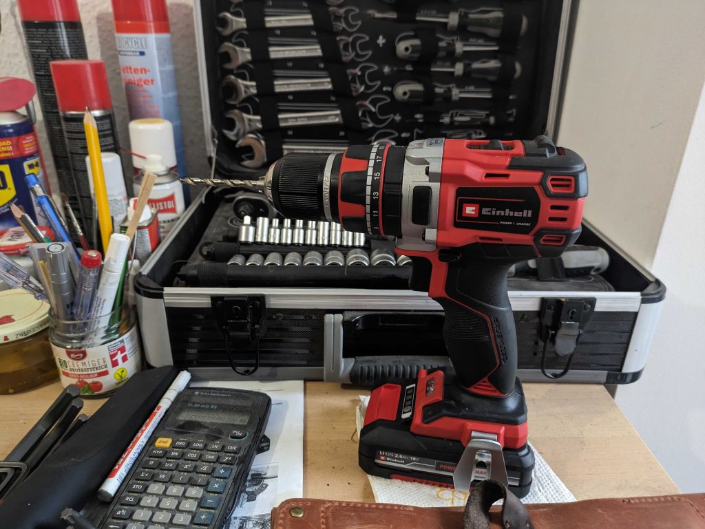 Einhell TP-CD 1850 Li-i BL Akkuschrauber auf einer Werkbank vor einem Werkzeugkoffer aus der Nähe