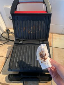 George Foreman ‎25030-56 Kontaktgrill beim Entfernen der Grillreste mit einem Küchenkrepp