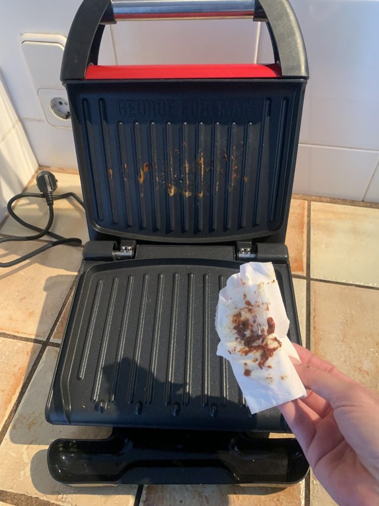 George Foreman ‎25030-56 Kontaktgrill beim Entfernen der Grillreste mit einem Küchenkrepp