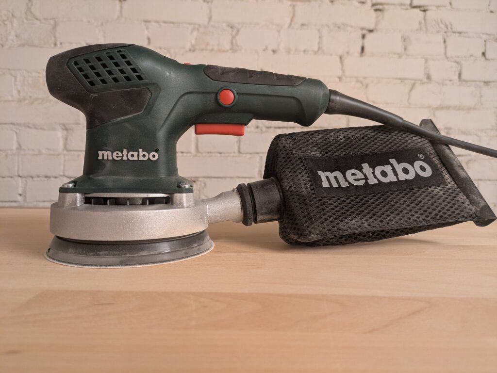 Metabo SXE 3125 Exzenterschleifer Titelbild mit Staub
