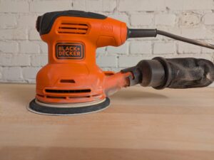 Titelbild des Black Decker BEW210 Exzenterschleifers mit Staub