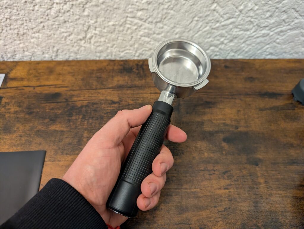 Kaffee-Pad der Krups Precision XP801T Siebträgermaschine in der Hand