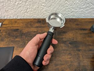 Kaffee-Pad der Krups Precision XP801T Siebträgermaschine in der Hand