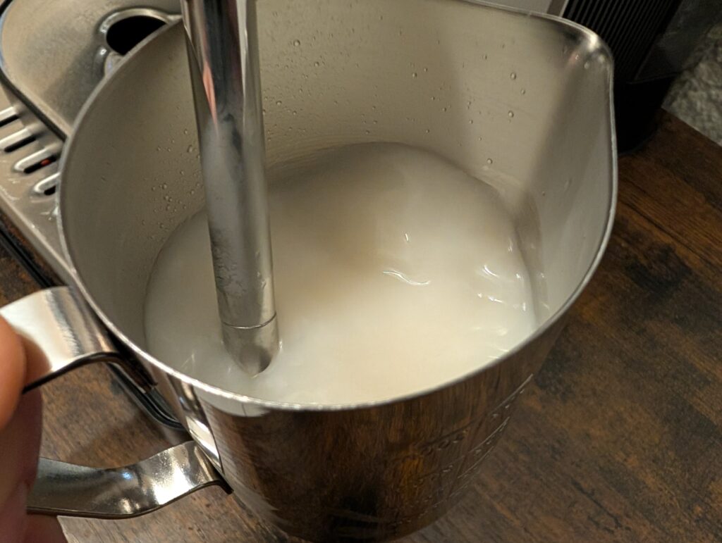 Milchkanne der Krups Precision XP801T Siebträgermaschine mit Milch in der Nahansicht