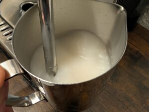 Milchkanne der Krups Precision XP801T Siebträgermaschine mit Milch in der Nahansicht